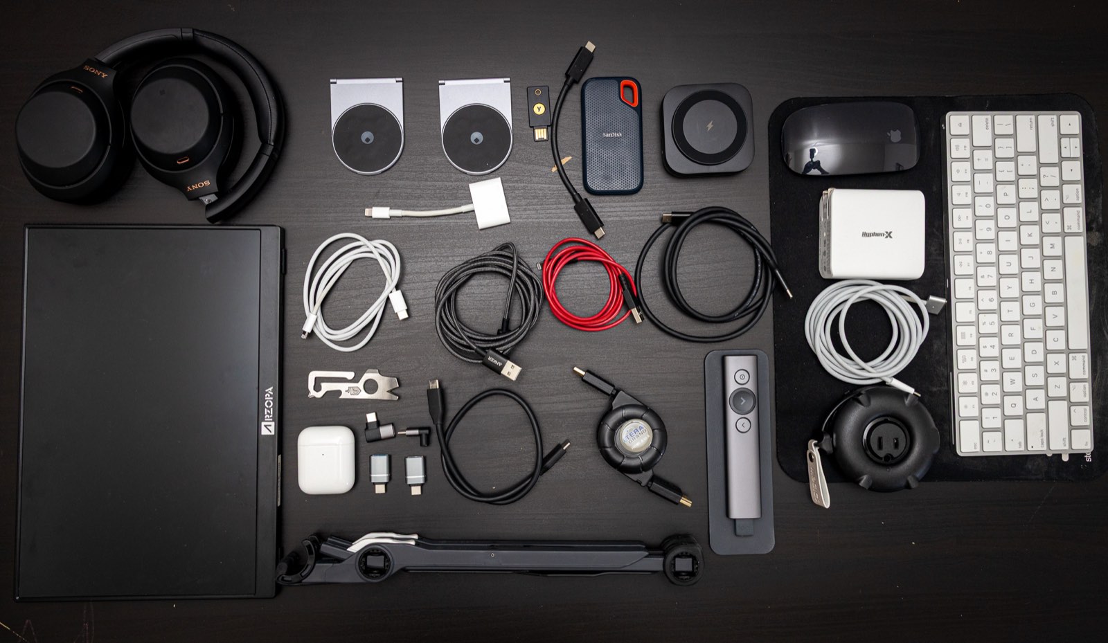 The full kit laid out flat: headphones, laptop stand, cables, keyboard, presenter, portable monitor and pouch